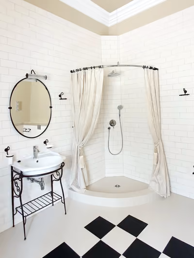 Small vintage-style bathroom with white subway-tile walls, a wrought-iron pedestal sink stand, an oval mirror, and a black-and-white diamond checkerboard tile floor