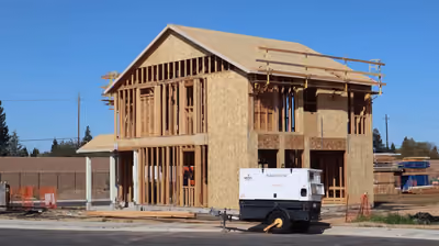 New home under construction with full wood framing against a blue sky