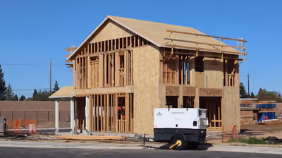 Custom home under construction showing full wood framing on a new foundation