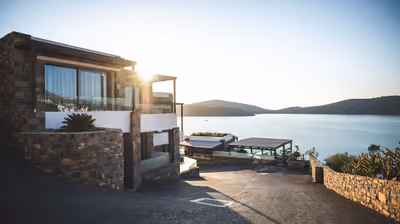 Luxury home with a stone facade at sunset overlooking the water