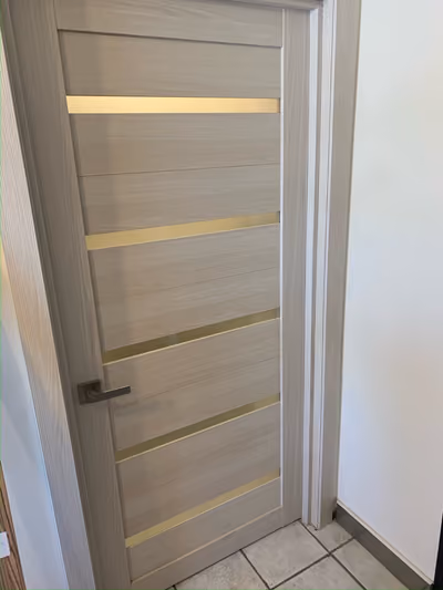 Close-up of an interior door with horizontal frosted-glass inlay strips and a modern lever handle