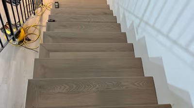 Staircase mid-installation with new wood-look laminate flooring on the treads