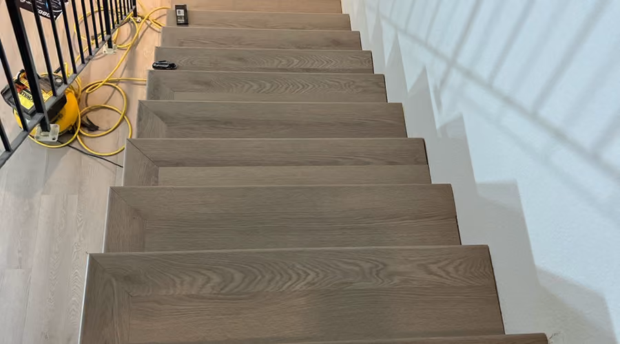 Staircase mid-installation with new wood-look laminate flooring on the treads