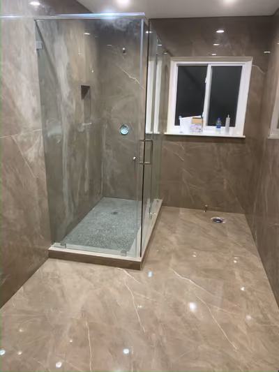 Finished glass-enclosed shower with a built-in niche and glossy tile walls in a renovated bathroom