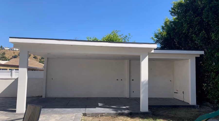 Newly built covered patio structure with clean white stucco columns and a paver patio