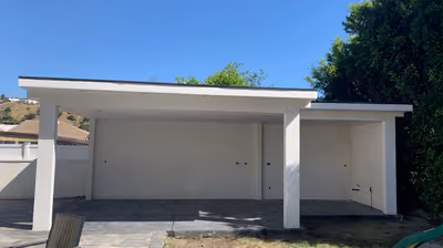 Newly built covered patio structure with clean white stucco columns and a paver patio
