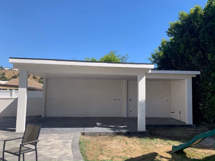 The same patio cover finished in clean white stucco with smooth columns and a paver patio