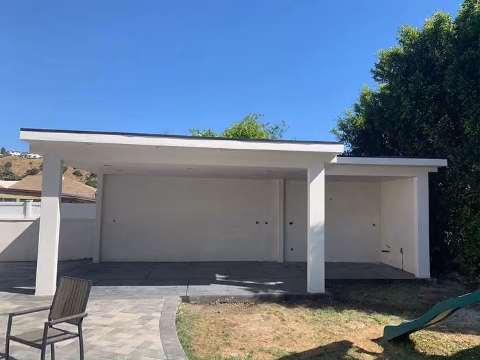 The same patio cover finished in clean white stucco with smooth columns and a paver patio
