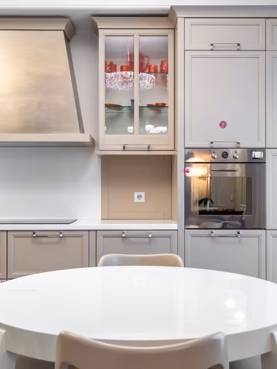 Classic cream-cabinet kitchen with glass-front uppers, a round dining table, and built-in oven