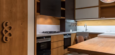 Modern remodeled kitchen with warm wood cabinetry, island seating, and integrated stainless appliances