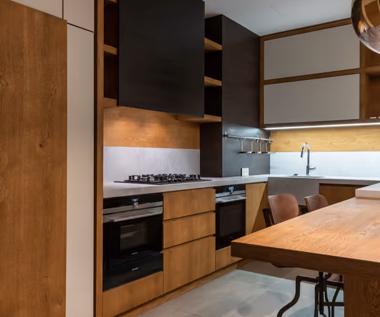 Modern remodeled kitchen with warm wood cabinetry, island seating, and integrated stainless appliances