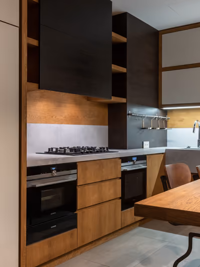 Modern remodeled kitchen with warm wood cabinetry, island seating, and integrated stainless appliances