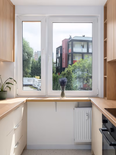 Small galley-style kitchen remodel with light oak cabinetry on two facing walls, wood countertops, a black induction cooktop, and a window at the end of the narrow layout