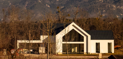 Modern luxury home with a dramatic glass gable against snow-capped mountains