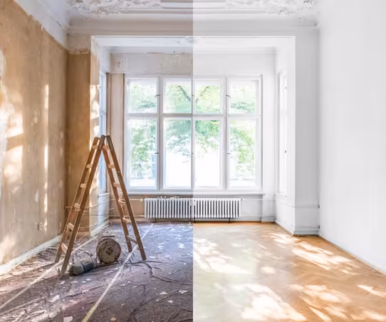 Before-and-after split image of a room mid-renovation: stripped walls and bare subfloor on the left, finished white walls and herringbone hardwood flooring on the right