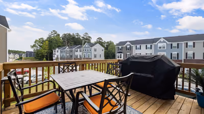 Elevated backyard wood deck with a dining table, chairs, and a covered gas grill