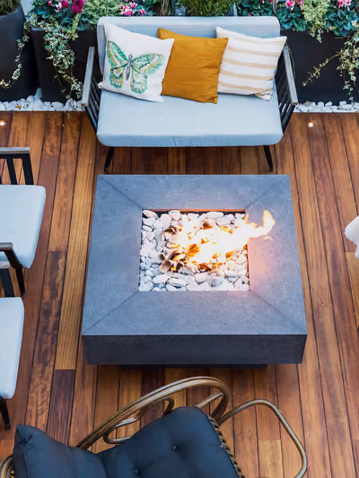 Wood deck lounge area with modern outdoor furniture arranged around a built-in fire pit